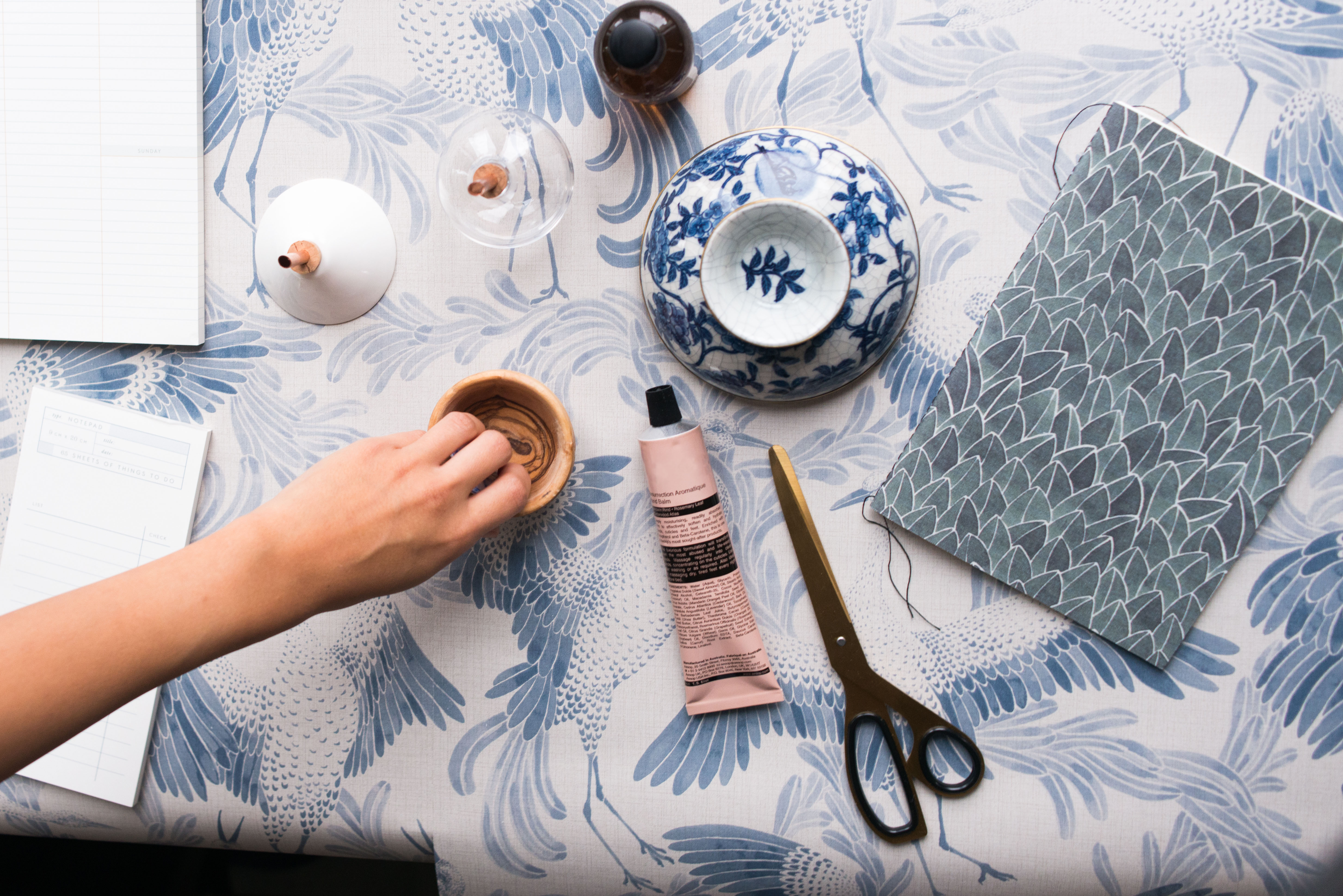 En person skapar något på ett bord. På bordet finns lim, sax,  papper och lera.